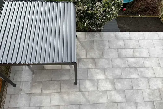 Aerial view of paved garden with Proteus Grey aluminium pergola with roof louvres closed. Design by Smith and Varney Landscapes.