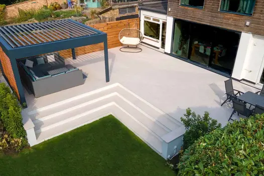 Raised patio with Egyptian Light Porcelain Paving tiles, matching steps, and integrated outdoor seating.