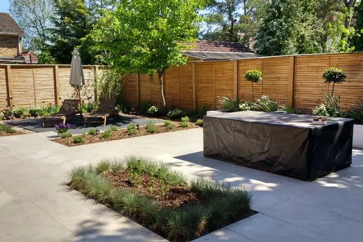 Fenced garden, mostly paved in Silver Grey Porcelain tiles, with rectangular flowerbeds set in paving. By Rhoda Maw Garden Design.