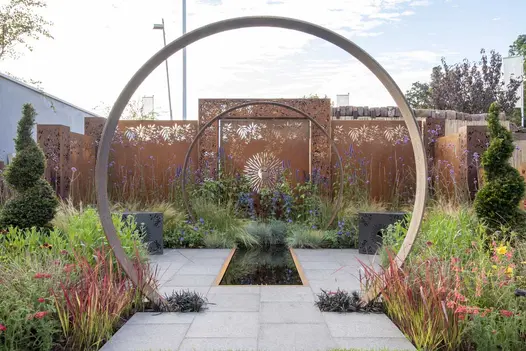 Dark Grey Granite paving with grassy planting in Sunburst Garden, RHS Hampton Court 2022 by Charlie Bloom and Simon Webster.