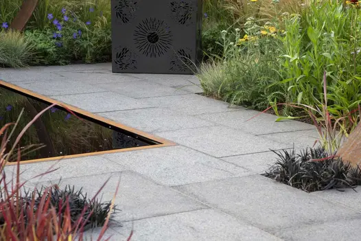 Dark Grey Granite paving with Corten steel edged pond, metal cube seat and grassy planting. Design by Charlie Bloom, Hampton Court.