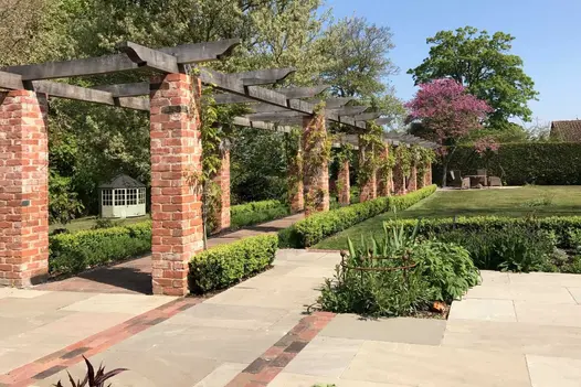 Long colonnade of square pillars of Romsey Antique facing bricks topped with timber beam frame. Design by Roger Gladwell.