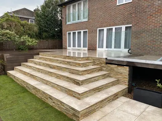 6 deep steps in Frosty Grey Porcelain with stone-clad risers ascend from lawn to matching patio with 2 sets of doors from house.