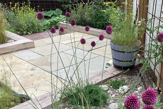 View through purple flowers shows off Antique Yellow Limestone with  wild planting all around. Design by Sally Bower.