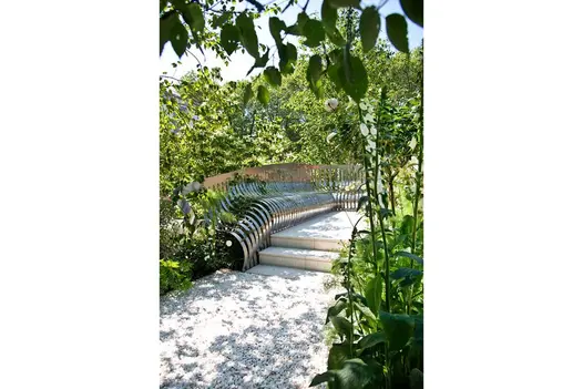Two Sandy White Porcelain steps with decorated risers up to matching path along length of curved steel bench at RHS Chelsea 2014.