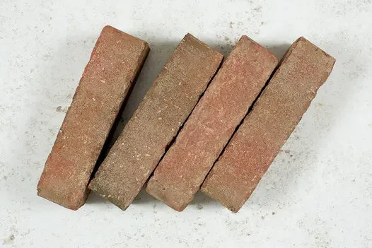 4 Seville brick pavers laid at slant and on edge on pale background, showing tumbled edges and orangey colour.