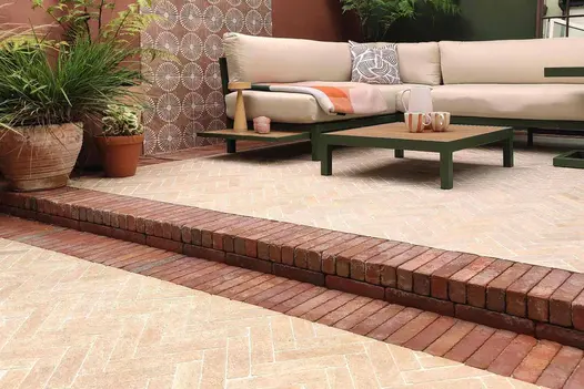 Limestone pavers laid on patio with seville clay pavers used as border and step up to outdoor sofa with terracotta plant pots.