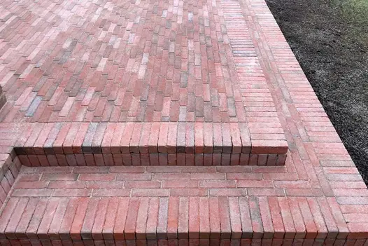 Raised paved area of Seville clay pavers with wrap-around step both edged with soldier course. Design by Rebecca Morgan.