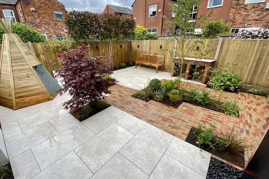 Wooden tepee in corner of fenced garden partly paved with mix of Westminster and Seville Clay Pavers. Built by Bark Brick & Block.
