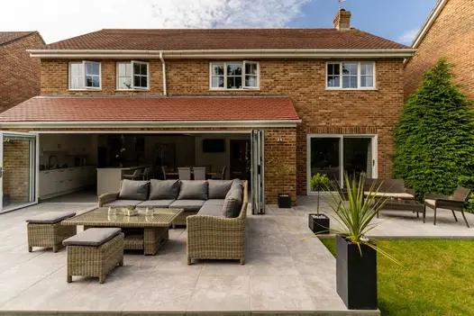 Indoor-outdoor space created by large kitchen with bifold doors opening onto Silver Contro Porcelain patio by Gadsden Gardens.