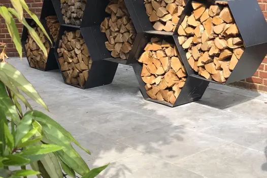 A wood store made of black hexagonal cells sits on pale-grey Silver Contro Porcelain tiles, jointed with Norcros grout.
