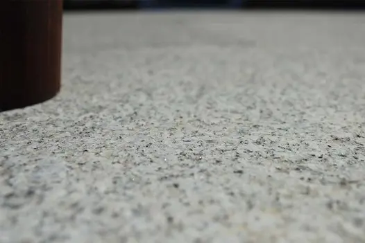 Mega close-up of Silver Grey granite slab, only partially in focus, showing stone’s black speckling on even background. 