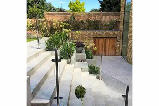 Silver grey porcelain chamfered step treads and risers, ascending to left, between terraced beds and glass and steel banister.