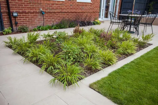 Florence Beige porcelain edging separates lawn from planted bed set into matching patio paving, by Simon Orchard Garden Design.