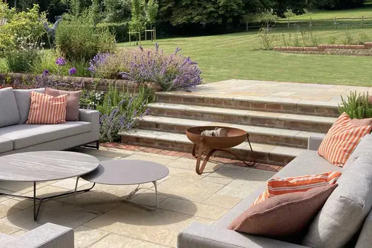 4 Antique Yellow limestone outdoor steps descend from lawn to matching patio with firebowl. Built by Simon Scott Landscaping.