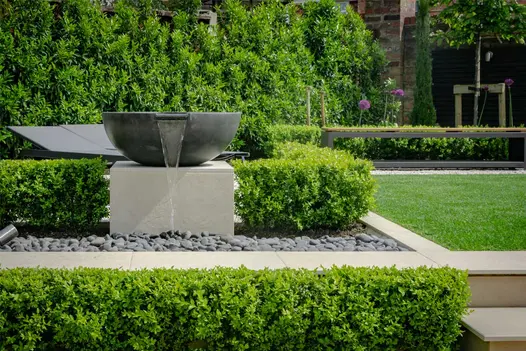 Large bowl spills water onto pebbles in area outlined in Slab Khaki Porcelain Pool Coping with chamfer. Design by Robert Hughes.
