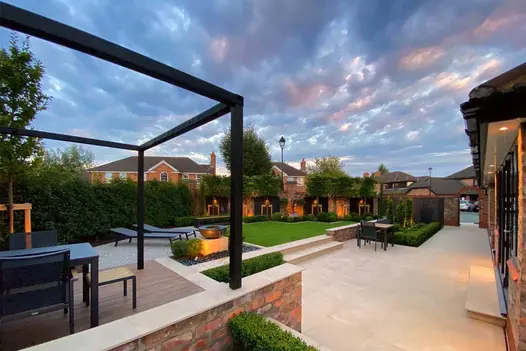 Lawned garden by Robert Hughes, with large patio in Slab Khaki Porcelain paving, with matching wall coping, mowing strips and steps.