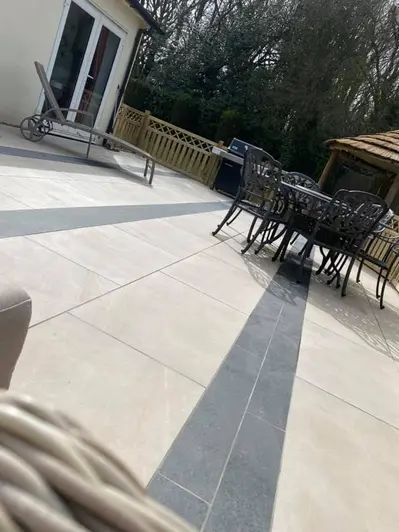 Side view of Platinum Grey Porcelain planks used with light beige coloured porcelain paving. Pergola and garden furniture in the distance.