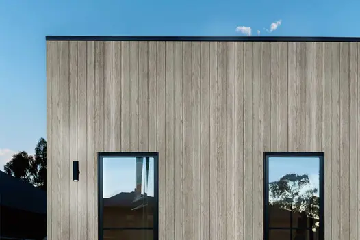 Modern home exterior clad in Smoked Oak Millboard Board & Batten, showcasing a vertical layout and pale weathered timber effect.