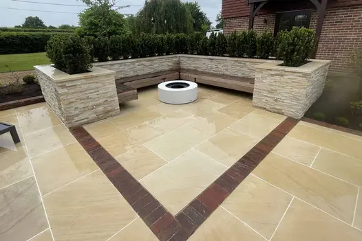 Fire pit seating area with integrated benches against stone-clad planters. Harvest Sawn Sandstone enhances the warm and inviting atmosphere.