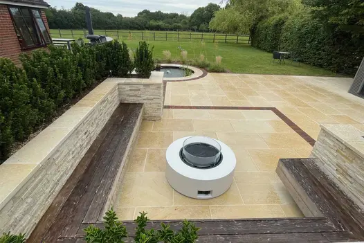 Outdoor seating area with built-in benches, surrounded by cladded planters, paved with Harvest Sawn Sandstone.