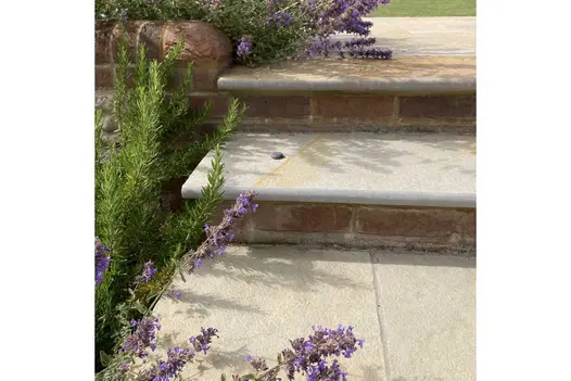 Pebble on Antique Yellow limestone bullnose step with brick riser, next to rosemary bush. Design by Bo Cook, built by Simon Scott.