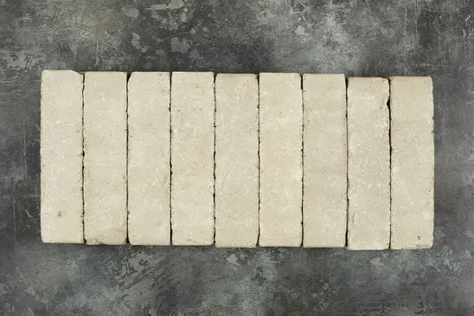 9 Stone Grey clay pavers laid edge-on in a row against dark background, showing pale buff and white tones. Free UK delivery available.