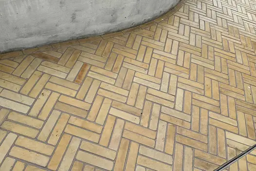 Close-up of Harvest stone pavers in double herringbone pattern, highlighting their warm pastel colours and textured, tumbled surface.