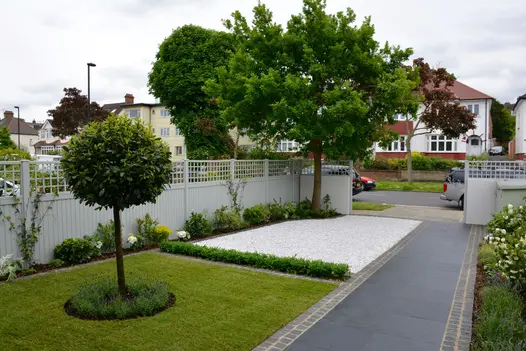Midnight Black limestone stone paving, edged with setts, slopes up past 2 large squares of white gravel and lawn in front garden.