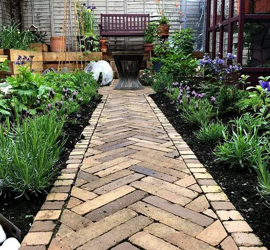 A garden path made of Aldridge clay pavers, flanked by flowerbeds, demonstrating their suitability for garden pathways and decorative entrances.