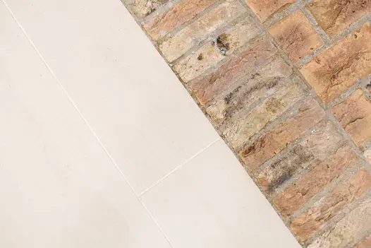 Faro Porcelain paving with white grout laid hard next to a soldier course of clay pavers, showing contrast in colour and texture.