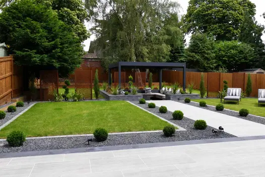 Landscaped back garden with a large porcelain patio, porcelain paths, lawn and sunken seating area covered by a metal pergola.