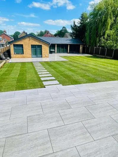 Travertine Dark porcelain patio with large lawn leading to another patio area with stepping stones.