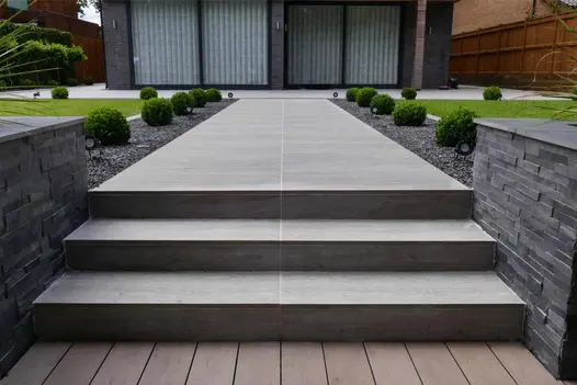 Set of Travertine Dark porcelain steps and long path leading towards the patio doors of a modern house.