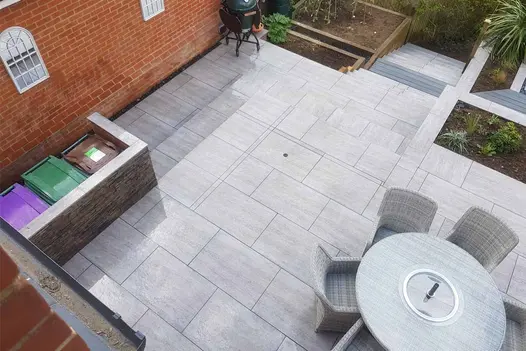Travertine Dark porcelain patio and steps leading from a top terrace down to an overgrown garden area.