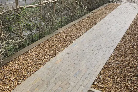 Antique Yellow Stone Pavers used as path with pebbles either side, growing plants used as hedges to the left.