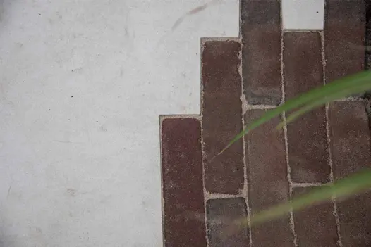 Close up view of Venetian Beige porcelain paving that has been accurately cut around some red clay pavers.