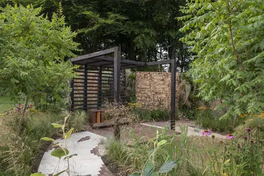 Path of Venetian Beige Porcelain pavers with clay detail runs to pergola in RHS Tatton Park show garden by Topoforma Landscape.