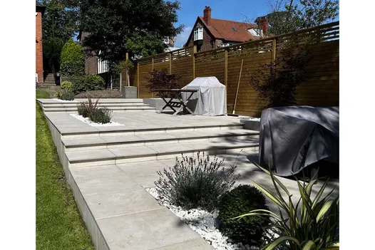 Multi level paved area using Venetian Beige Porcelain Paving, planting areas on each level with white decorative stones.