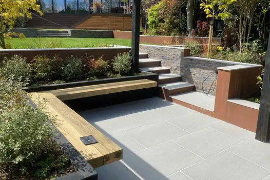 Steps down from lawn to sunken seating area with cantilevered bench, walls faced with Vintage Steel Designclad porcelain cladding.