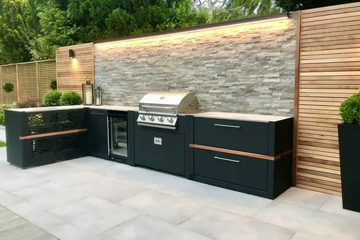 Outside cooking area including an impressive BBQ and grill, with Grey Wall Cladding and downlights, with Venetian Grey Porcelain Paving.