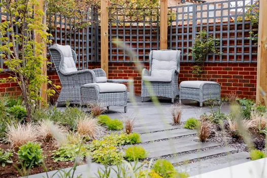 Patio of Platinum Plank Paving edged by walls with grey trellis. Low planting in beds. Built by VU Garden Design and Landscaping.