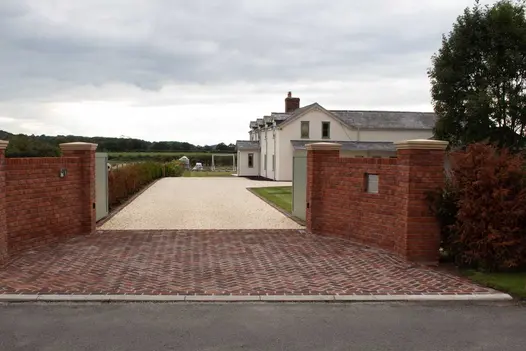 Deep apron of Dorset Antique Belgian bricks at entrance to white gravel drive to house with lawn and children’s goal beyond.