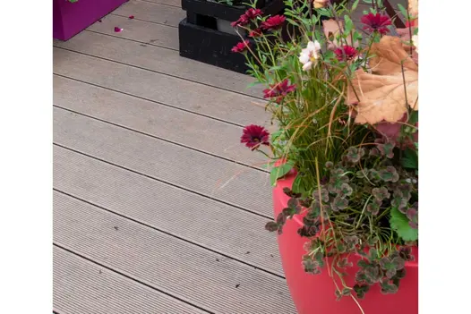 Planted orange pot sits on Warm Teak long composite decking boards. Cirrus Garden, RHS Chelsea 2022. Design by Jason Williams.