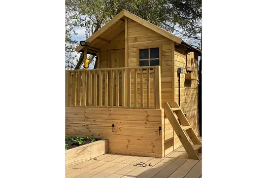 Chalet-style wooden playhouse rises above composite decking of Warm Teak Brushed Designboard. Design by Gardens of the Future.