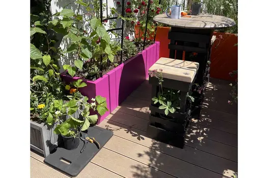 Kneeler and secateurs on Warm Teak Decking composite, with veg-planted troughs and table and stool. Design by the Cloud Gardener.