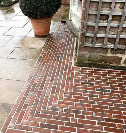 Winton Clay pavers laid with cementitious jointing create strip around corner of house next to very large flower pot with shrub